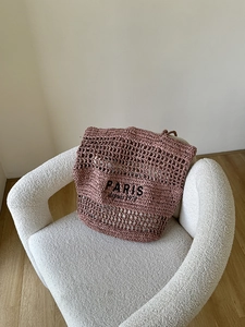 Detailansicht der durchbrochenen Flechtstruktur und schwarzen Paris-Stickerei auf rosa Tasche