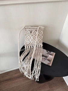 Detailed close-up of handmade bohemian fringe crossbody bag in cream woven cotton