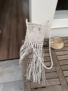 Close-up of handmade beige macramé crossbody bag with long tassels and woven strap