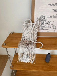 Close-up of bohemian handmade woven bag with tassels and intricate cotton rope texture