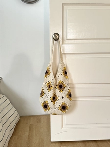 Detailed texture of handmade sunflower crochet tote bag hanging on a white wooden door