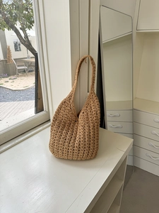 Macro detail of hand-woven straw shoulder bag showing intricate hollow crochet patterns