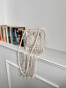 Detail of bohemian macramé woven bag featuring fringe tassels and diamond pattern