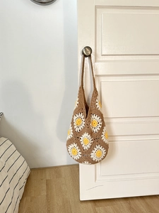 Close-up of handmade crochet daisy pattern and woven texture on a brown shoulder bag