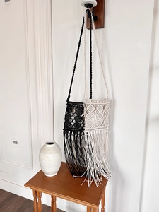 Detail of bohemian macramé crossbody bags with fringe in black and beige woven textures
