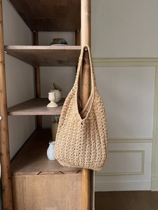 Detailed close-up of a hand-woven straw hobo bag showing crochet texture and hollow pattern