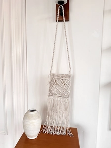Macro shot of bohemian woven texture and fringe details on a beige handmade crossbody bag