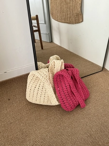 Detail of hollow hand-woven crochet beach bags in cream and deep rose pink colors