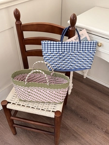 Detail of colorful hand-woven tote bags in blue and green plaid on a wooden chair