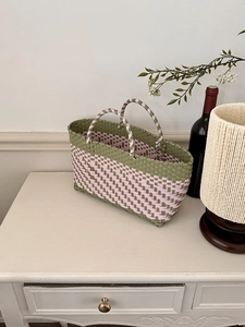 Detailed weave of olive and pink handmade woven basket bag on a minimalist cabinet