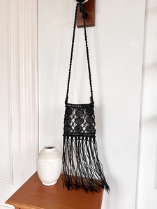 Detail of black boho macrame crossbody bag with long fringes and woven diamond patterns