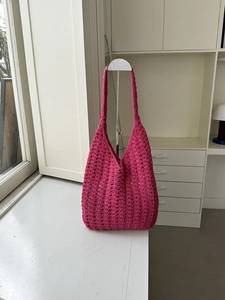 Detailed close-up of rose red hand-knitted crochet shoulder bag with hollow-out pattern