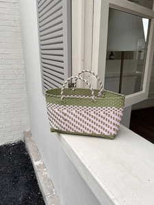 Close-up of olive green and pink hand-woven shopping basket with checkerboard pattern