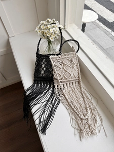 Detail of bohemian handmade woven bags with geometric mesh and long tassels in black and beige