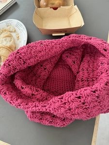 Detail of fuchsia hand-woven crochet bag with intricate hollowed-out floral pattern texture