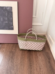 Detail of hand-woven checkered tote bag in olive green and pale pink plastic materials