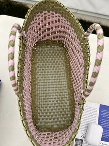 Close-up of handmade woven basket bag in vibrant green and pink geometric texture