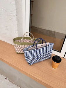 Detail of hand-woven checkered tote bags in olive green and navy blue with twin handles