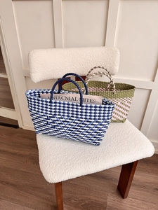 Detail of colorful hand-woven tote bags in blue-white and pink-green on a soft chair