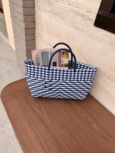 Detail of woven tote bag in blue and white on a wooden bench with lifestyle aesthetic