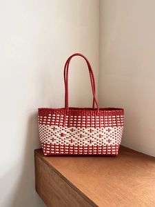 Close-up of red and white woven tote bag with detailed texture on a wooden surface