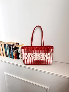 Detailed view of red and white woven tote bag in a minimalist home interior setting