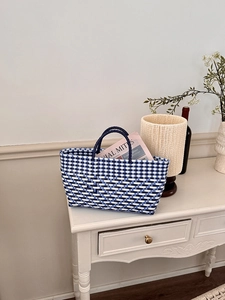 Close-up of blue and white checkered hand-woven tote bag with cylindrical dual handles