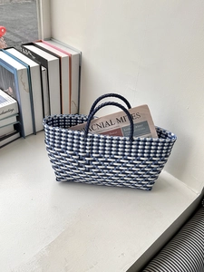 Detail of blue and white woven tote bag on window sill with a newspaper inside