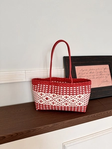 Close-up of red and white checkered woven tote bag with dual handles on wooden surface