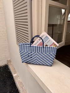 Close-up of a blue and white checkered woven tote bag placed on a stone window ledge