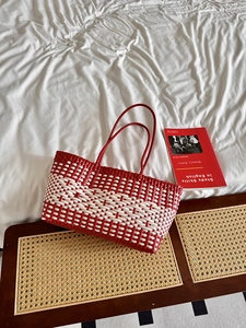 Detail of red and white hand-woven tote bag with intricate plastic weave texture