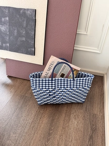 Detail of blue and white hand-woven tote bag with geometric texture on wood floor