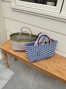 Close-up of handmade woven tote bags featuring colorful patterns on a rustic wooden bench