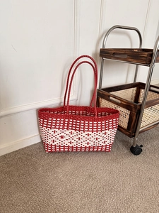 Detailed view of red and white woven plastic tote bag with durable reinforced handles