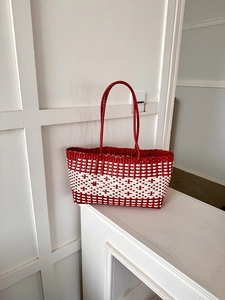 Close-up of red and white woven tote bag showing detailed lattice texture and handles