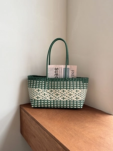 Detail of green and white checkered woven tote bag with round handles on wooden stand
