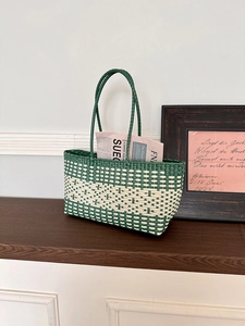 Detail of woven tote bag showing green and beige lattice texture and slim handle