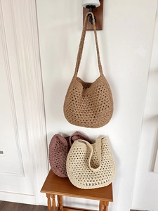 Détail de sacs cabas en paille tressée ajourée en couleurs kaki, beige et rose poudré