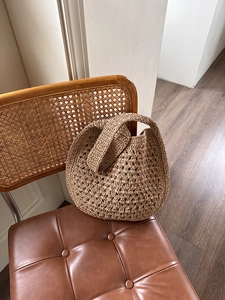 Détail d'un sac cabas en paille crocheté à la main sur une chaise rétro