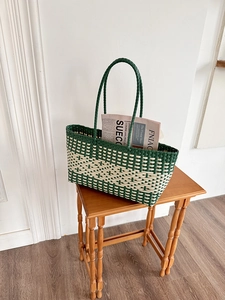Detail of green and beige checkered woven tote bag placed on a vintage wooden stool