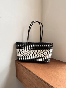 Close-up of black and white checkered woven tote bag texture on a wooden table