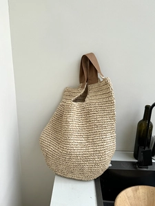 Minimalist woven straw shoulder bag with brown leather handles for summer beach vacations