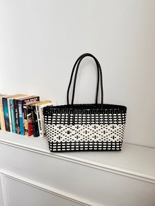 Detail of hand-woven tote bag with black and white checkered pattern on a shelf
