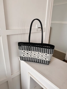 Detail of black and white woven tote bag texture on a white wooden surface