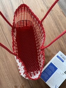 Detail view of the handwoven red and white beach tote bag on a wooden surface