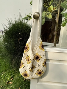 Handmade crochet sunflower tote bag in off-white cotton hanging on a vintage door handle