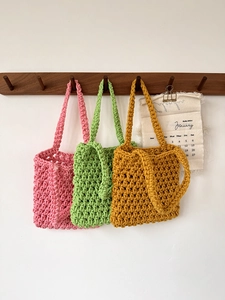 Detailed knit texture of handmade hollow mesh crochet tote bags in pink, green, and yellow