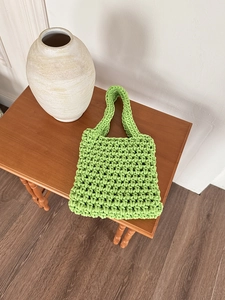 Detail of bright green handmade crochet beach bag showing woven texture and handle