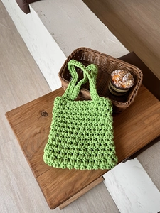 Detail of hand-woven hollow mesh net handbag in mint green for summer beach style