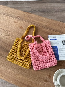 Detail of hand-woven hollow fishnet beach bags in mustard yellow and soft pink colors